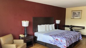 Une chambre d’hôtel équipée d’un lit, de lampes de chevet, d’une chaise, d’un bureau et d’un téléphone fixé au mur.