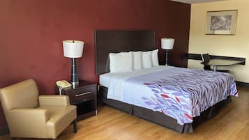 Habitación de hotel con cama, lámparas de noche, una silla, escritorio y teléfono en la pared.