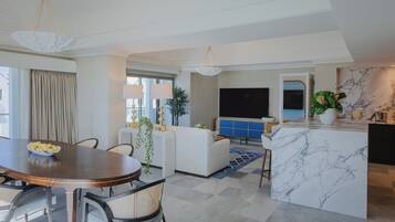 A modern living room with a dining area, a sofa, a TV, and a marble island.