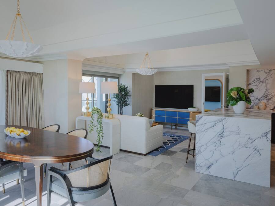 A modern living room with a dining area, a sofa, a TV, and a marble island.