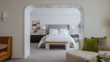 Una habitación de hotel moderna con una cama grande, un banco, un sofá y un comedor.
