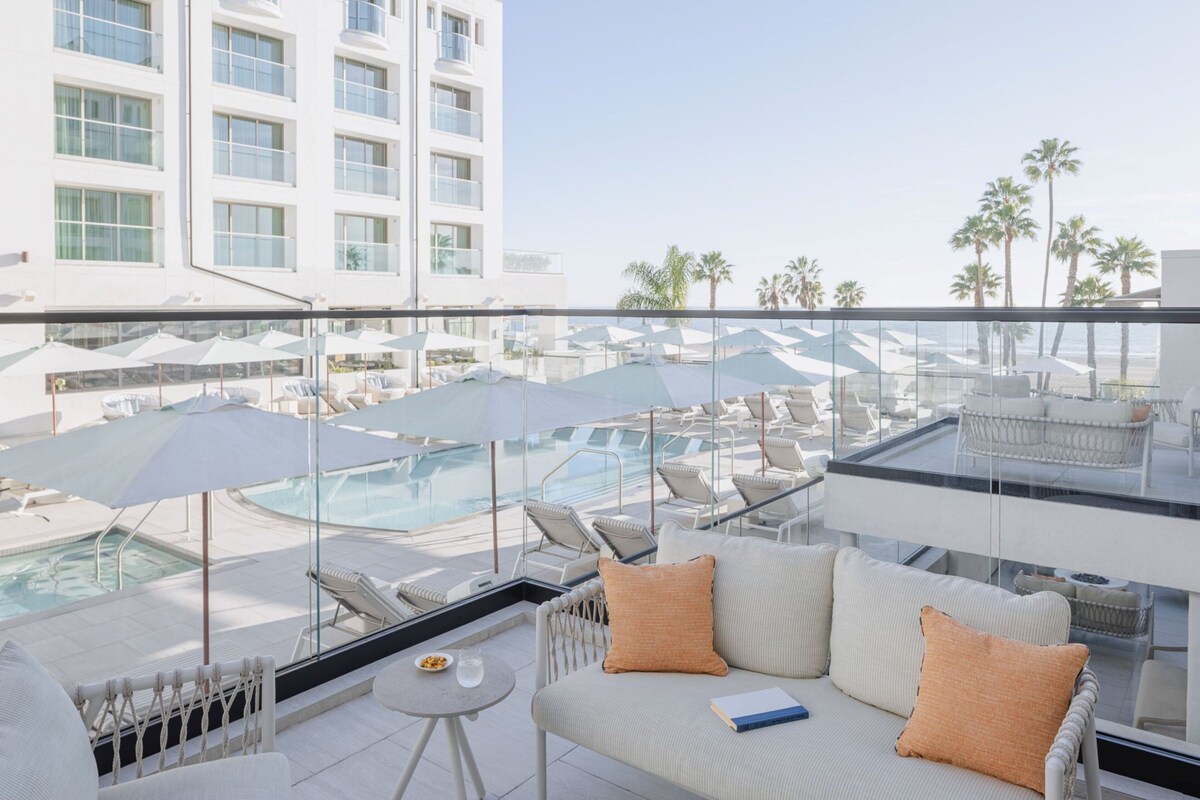 A rooftop lounge with a pool, lounge chairs, and umbrellas.