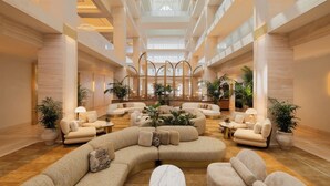A spacious lobby with a high ceiling, multiple seating areas, and large windows allowing natural light. - Regent Santa Monica Beach by IHG (Santa Monica)