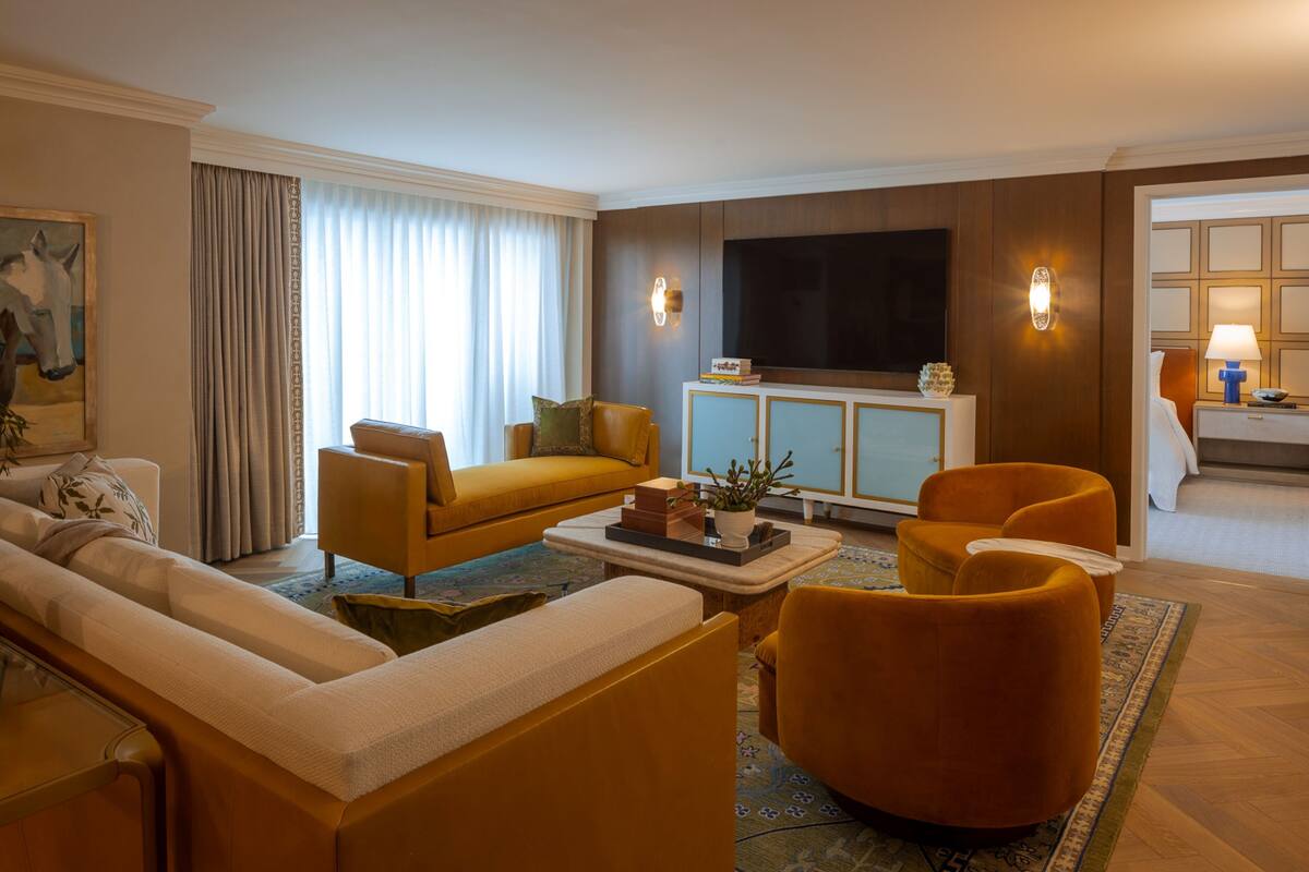 A modern living room with a sofa, armchairs, a coffee table, and a television.