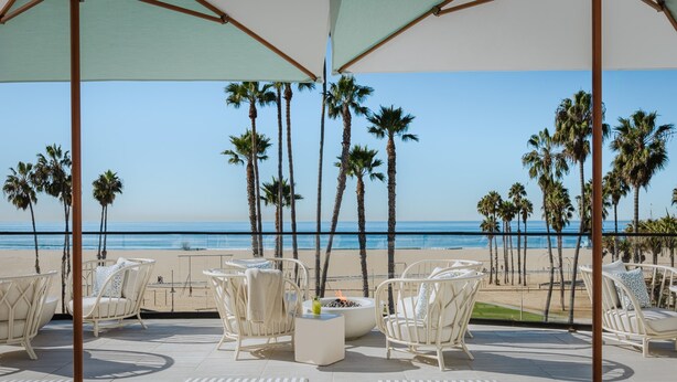 A beachside patio with white wicker furniture, a fire pit, and a view of the ocean. - Regent Santa Monica Beach by IHG (Santa Monica)