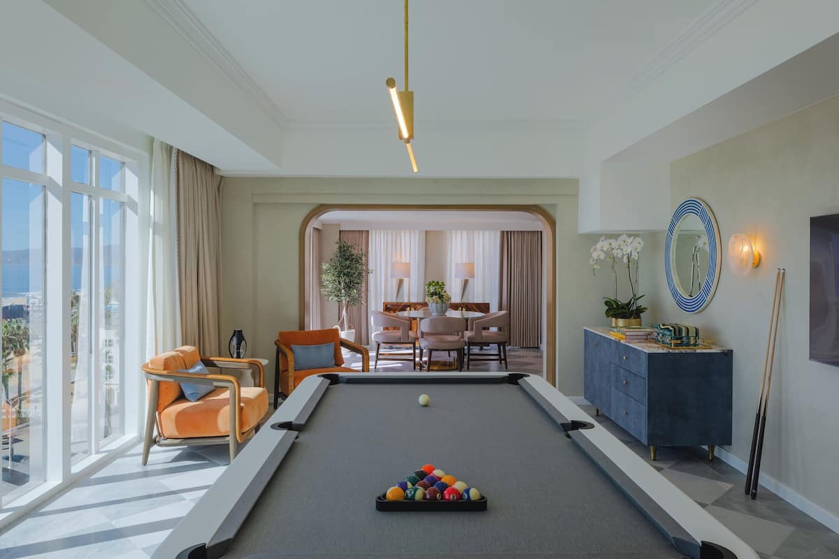 A pool table with balls, a sofa, a dining area, and a view of the outdoors.