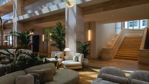A spacious lobby with a high ceiling, a staircase, and multiple seating areas. - Regent Santa Monica Beach by IHG (Santa Monica)