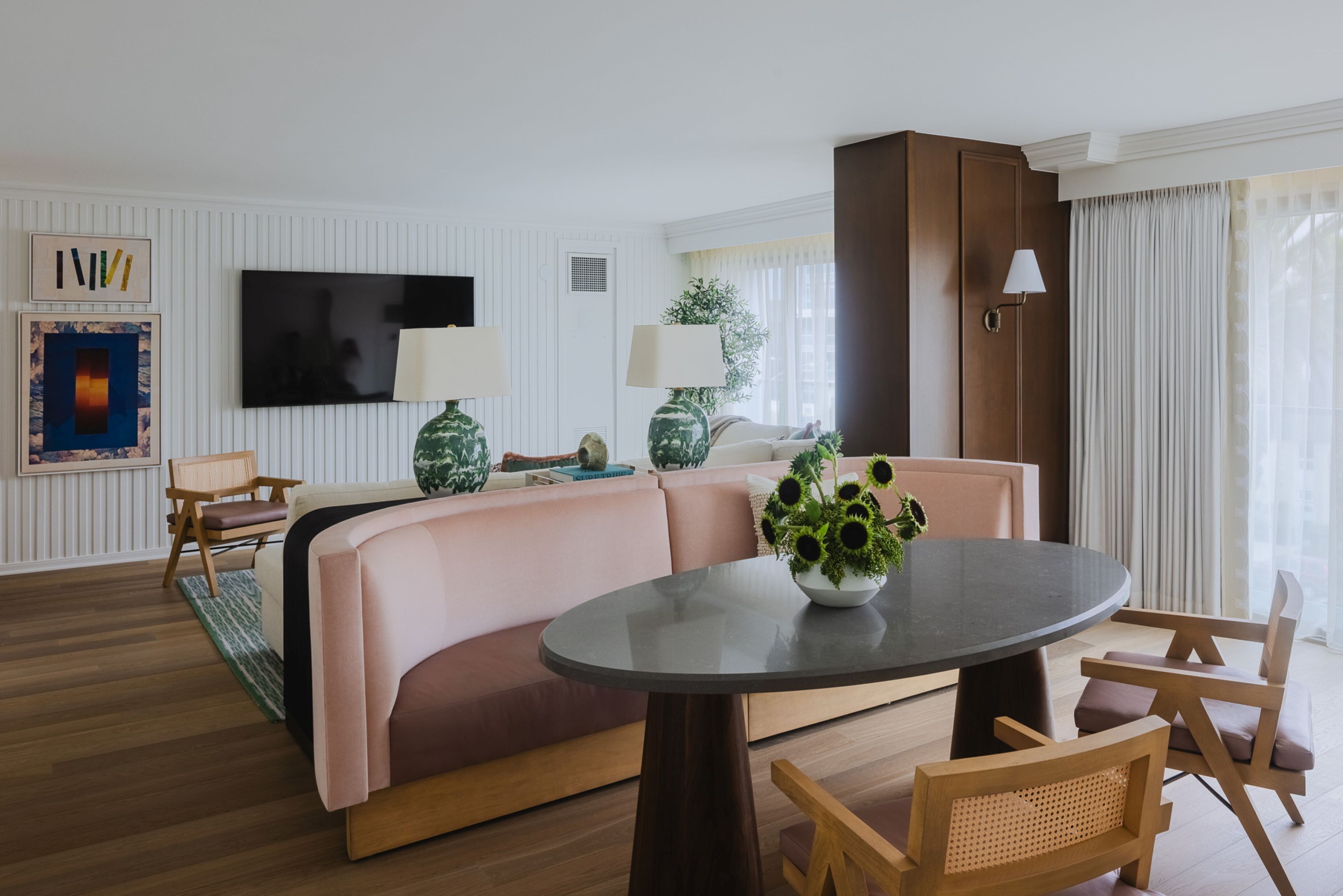 A modern living room with a round table, two sofas, a TV, and a cabinet.