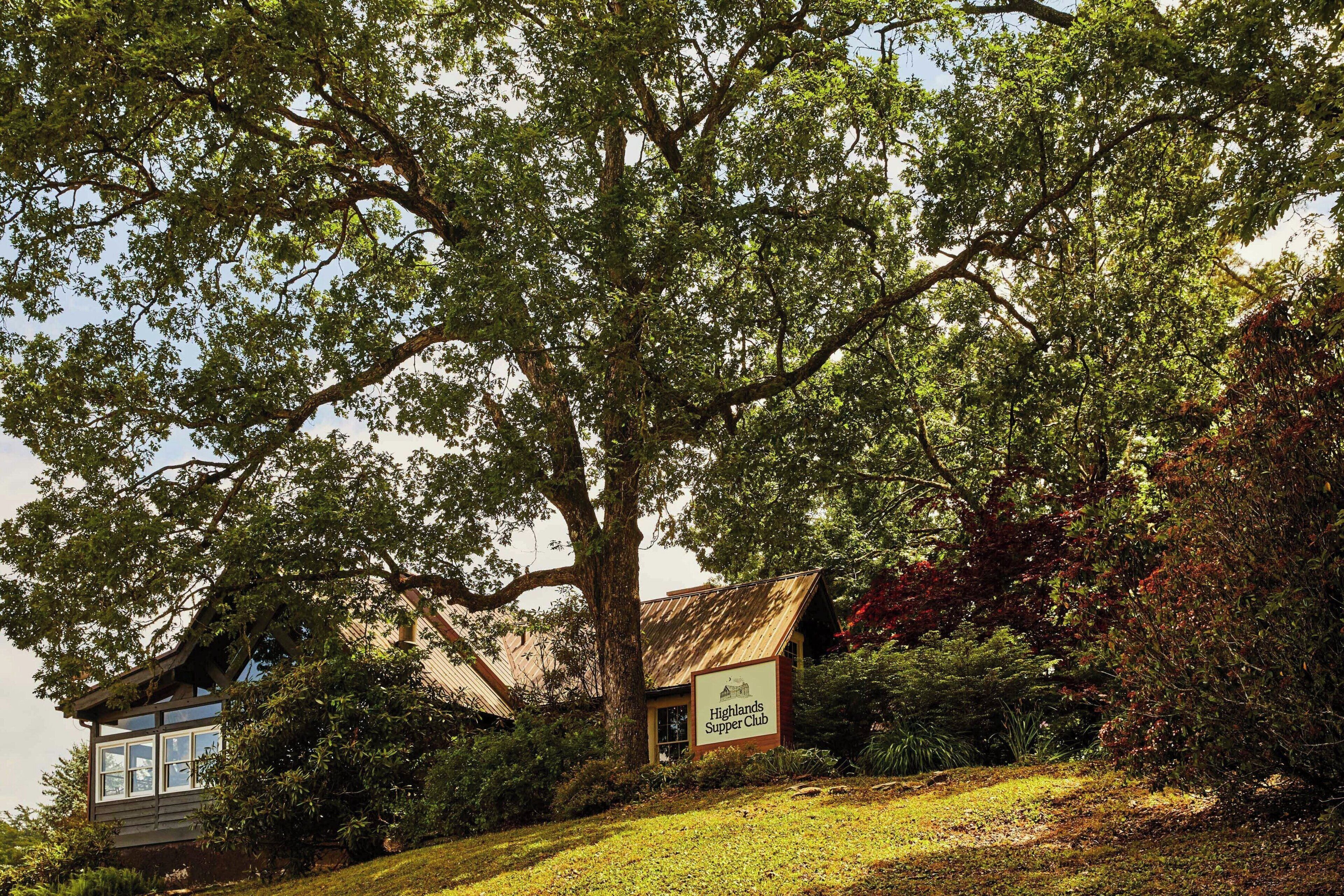 A building with a sign reading "Highlands Supper Club" surrounded by lush greenery.