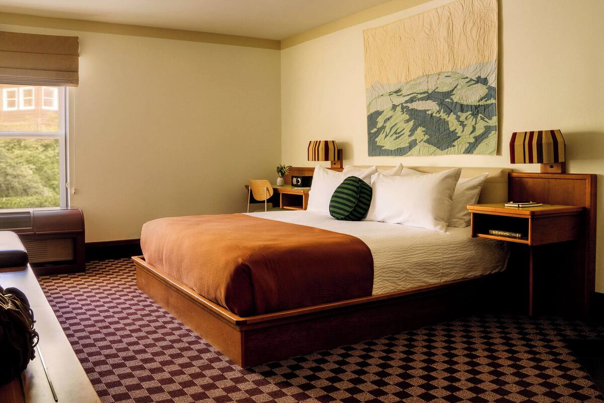 Une chambre d’hôtel avec un grand lit, un bureau, une chaise, une table de chevet et une fenêtre.