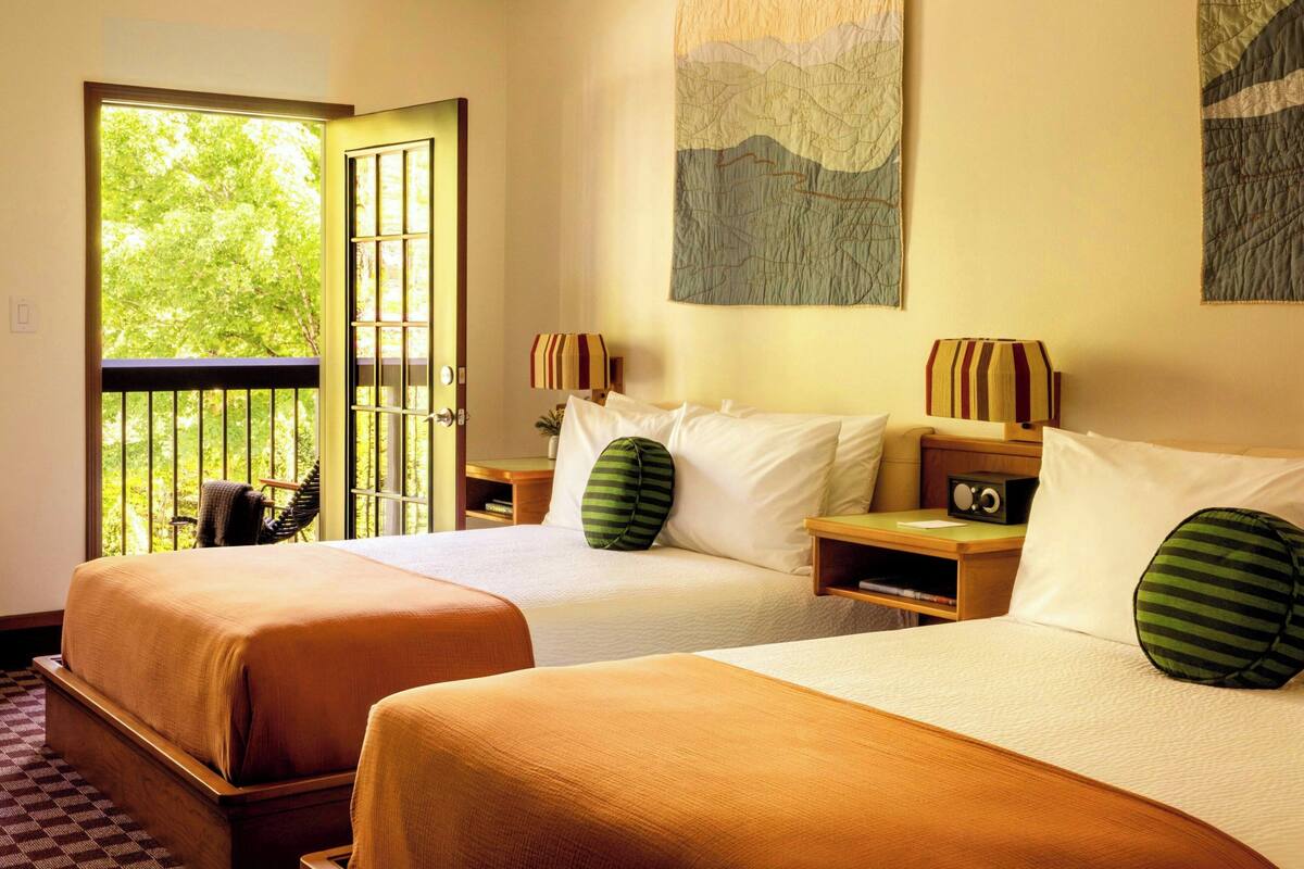 Une chambre d’hôtel avec deux lits, un balcon et des œuvres d’art aux murs.