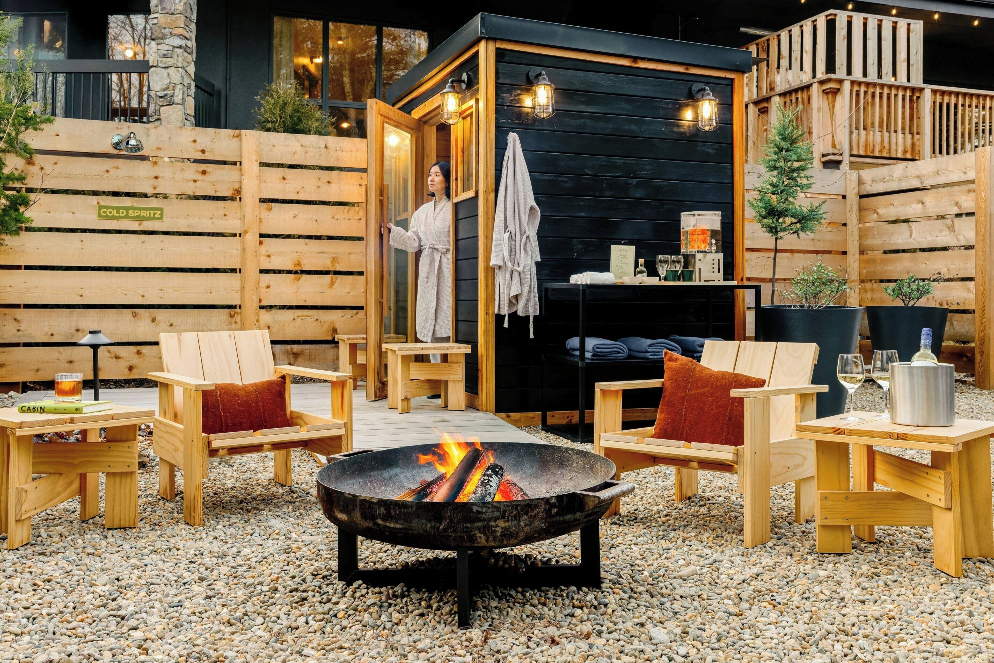 Un espace extérieur aménagé avec des meubles en bois, comprenant un foyer, des chaises et des tables en bois.
