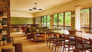Un vaste espace de vie agrémenté d’une grande fenêtre, d’une table à manger en bois et d’un coin salon confortable.