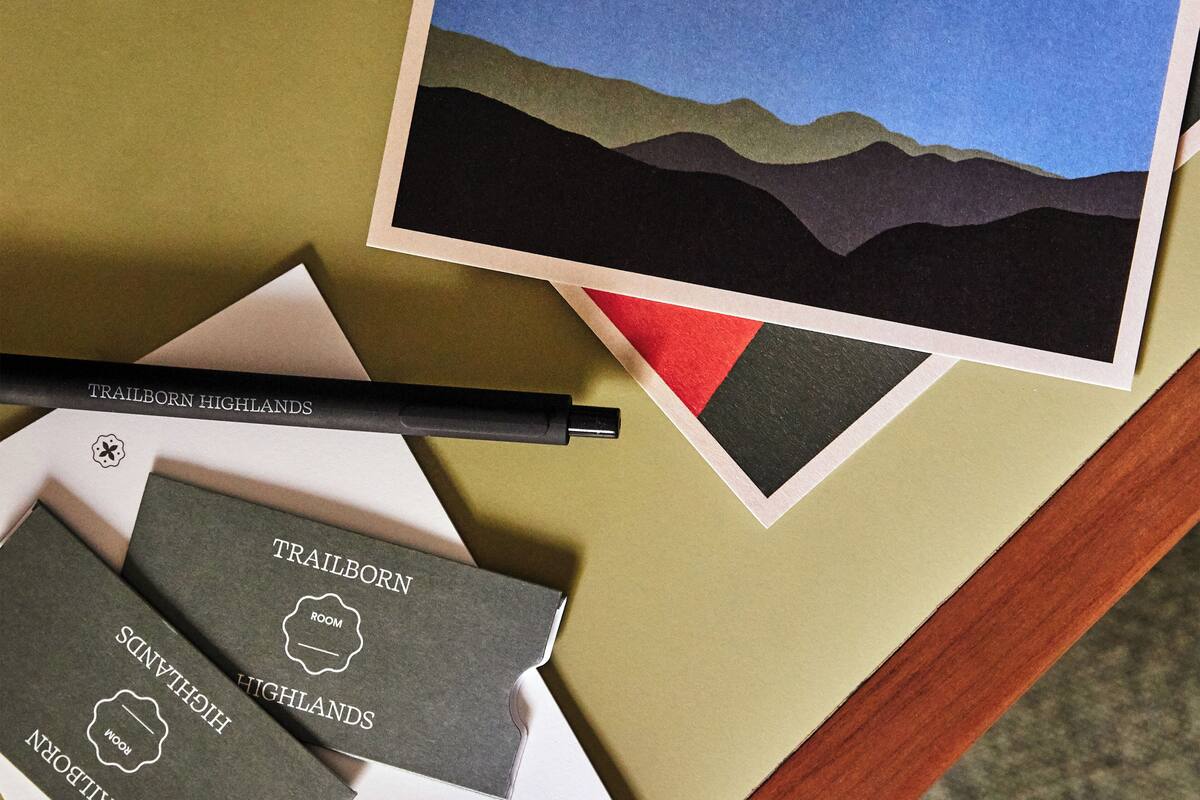 Une table avec une photo instantanée, un stylo et plusieurs brochures sur les différents types d’hébergement proposés par Trailborn Highlands.