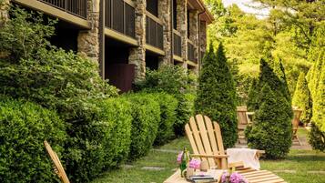 A stone building with a covered patio, outdoor seating, and a well-maintained garden.