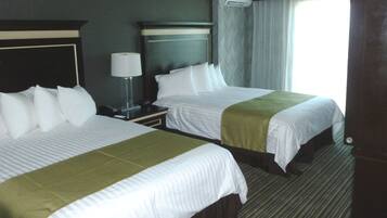 A hotel room with two beds, a nightstand with a lamp, and a window with curtains.