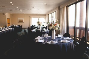 A banquet hall with round tables set for a formal event, featuring floral centerpieces and white table settings.