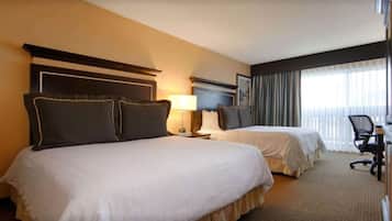 A hotel room with two beds, a desk, and a chair.