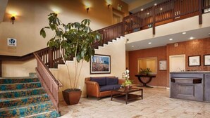 A spacious lobby with a staircase, a sofa, a coffee table, and a large potted plant. - Pacifica Lighthouse Hotel Trademark Collection by Wyndham (Pacifica)