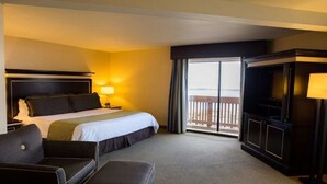 A hotel room with a bed, a desk, a chair, a TV, and a balcony with a view. - Pacifica Lighthouse Hotel Trademark Collection by Wyndham (Pacifica)