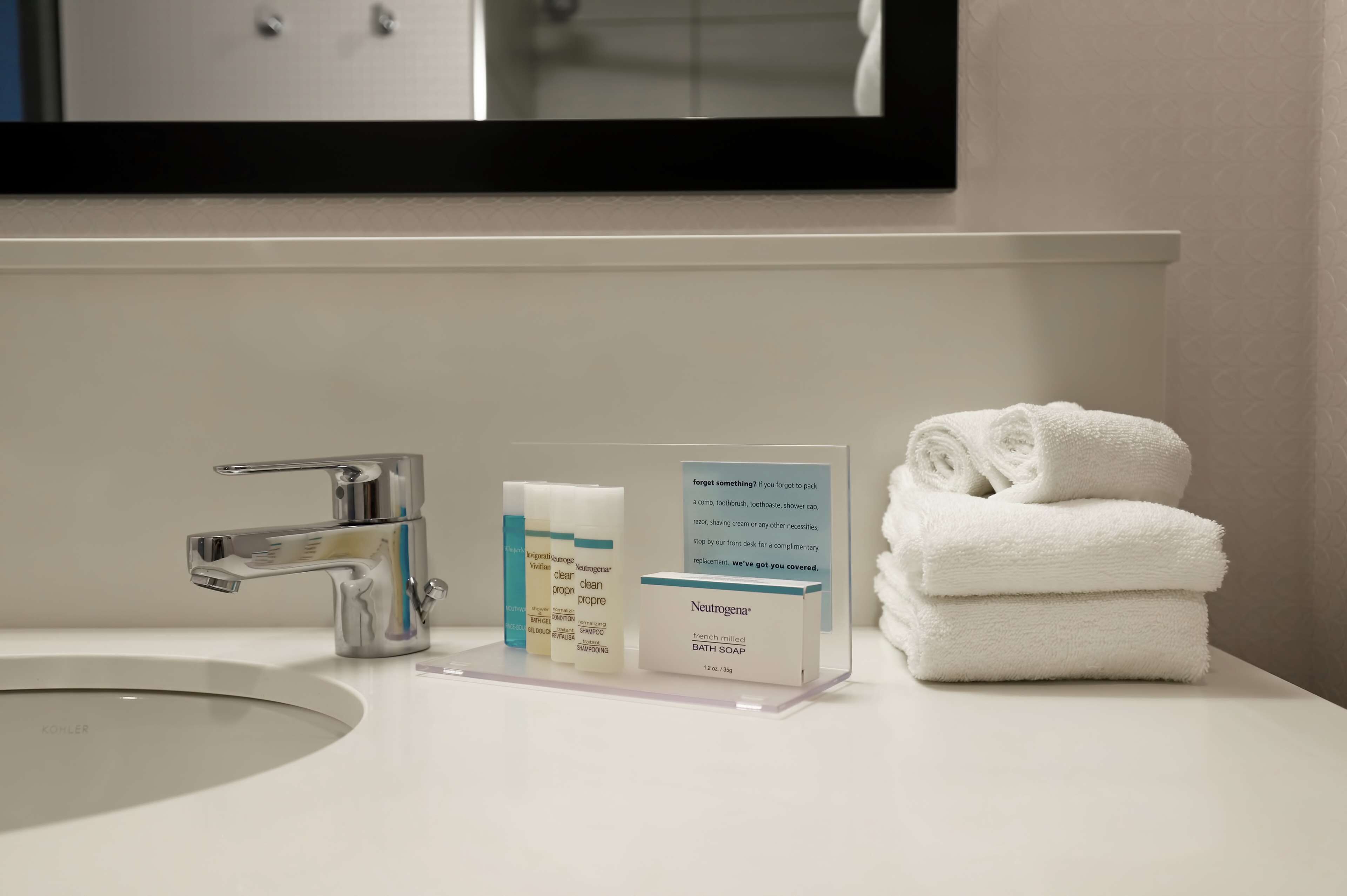 A bathroom sink with a chrome faucet, a Neutrogena bath soap box, and a stack of white towels.