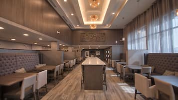 Un restaurante moderno con una barra central, techos altos y una variedad de opciones de asientos, incluyendo cabinas y mesas.