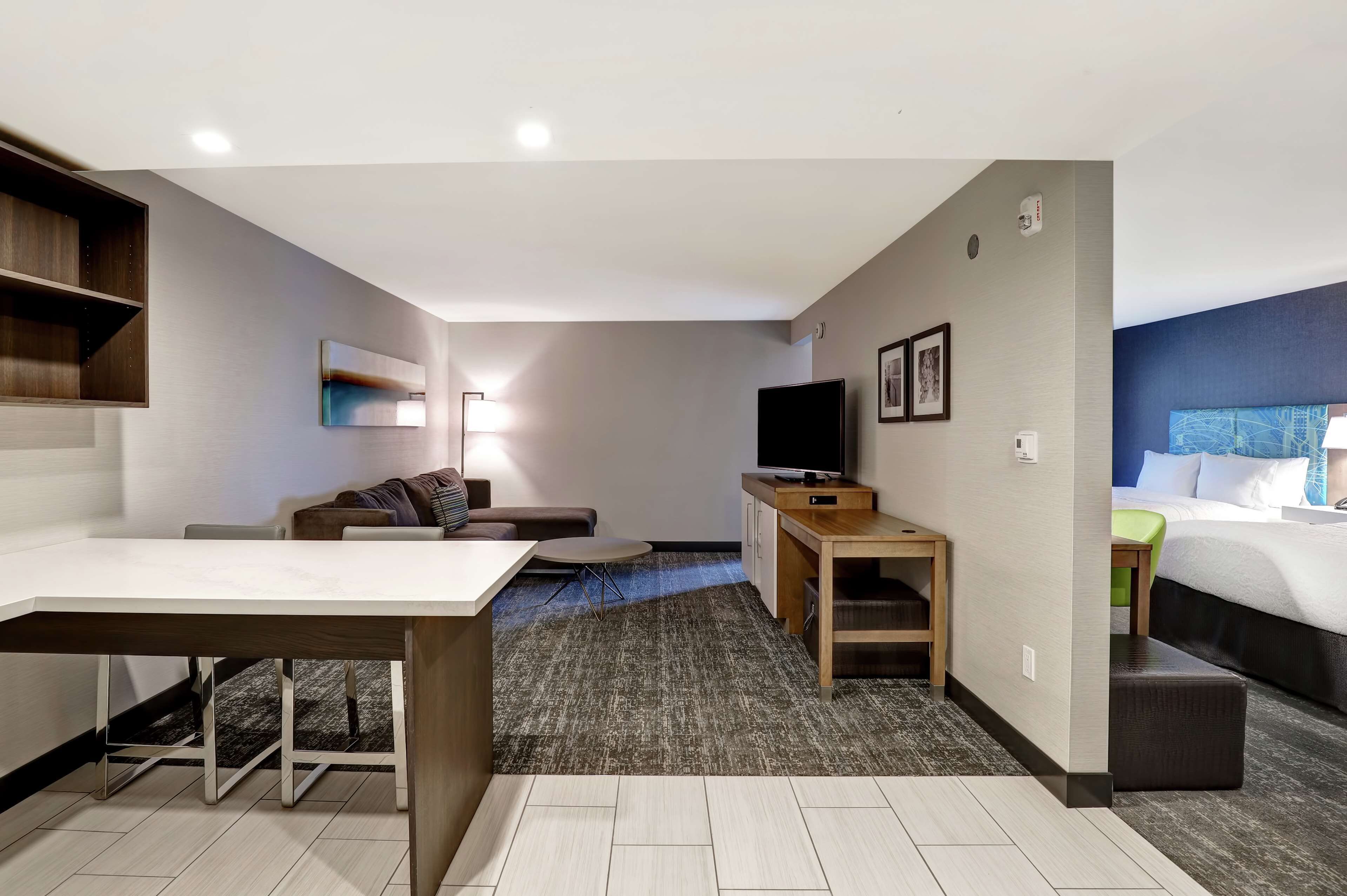 Ein modernes Hotelzimmer mit Essbereich, einer Couch, einem Fernseher und einem Bett.