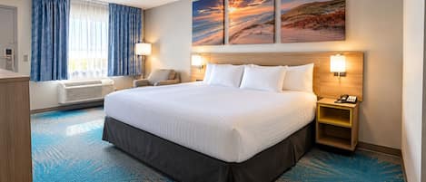 Habitación de hotel con una cama grande, un escritorio, una silla, una lámpara de escritorio, teléfono en la pared y una ventana con cortinas.