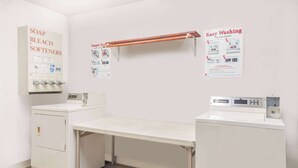 Ett tvättrum med tvättmaskin, torktumlare och en hylla med flaskor med tvättmedel.