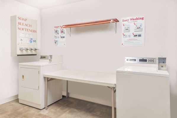 A laundry room with a washing machine, dryer, and a shelf with detergent bottles.