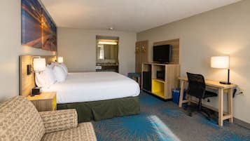A hotel room with a bed, a desk, a chair, a television, and a bathroom.