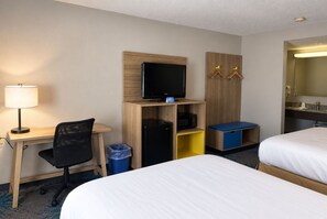 Habitación de hotel con dos camas, un escritorio con computadora, televisión y un pequeño espacio para sentarse.