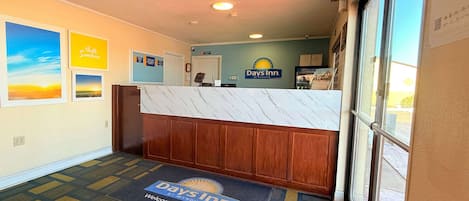 A reception area with a marble counter, a 'Days Inn' sign, and a welcome mat.
