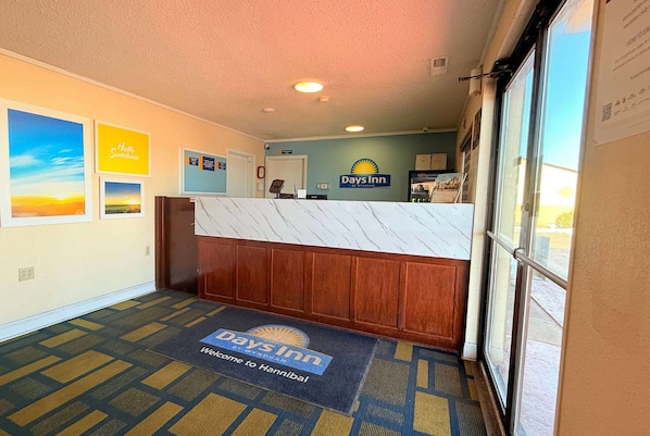 A reception area with a marble counter, a 'Days Inn' sign, and a welcome mat.