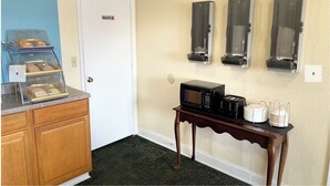 A kitchenette with a bread display, a microwave, a toaster, and a coffee maker on a small table. - Days Inn by Wyndham Hannibal (Hannibal)