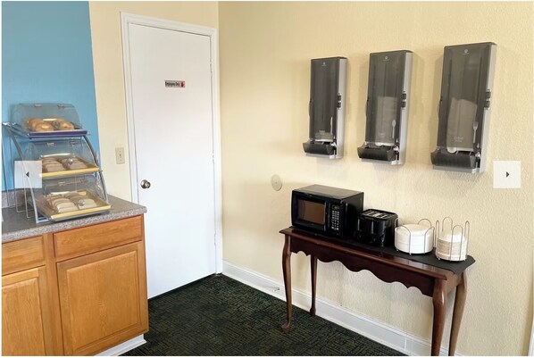 A kitchenette with a bread display, a microwave, a toaster, and a coffee maker on a small table.