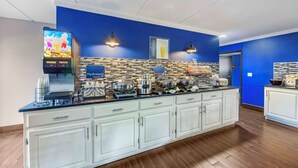 A modern kitchen area with a long counter, a juice bar, and a coffee machine.
