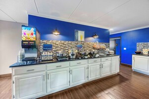 A modern kitchen area with a long counter, a juice bar, and a coffee machine.