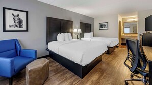 A hotel room with a large bed, a desk, a chair, a sofa, and two framed pictures on the wall.