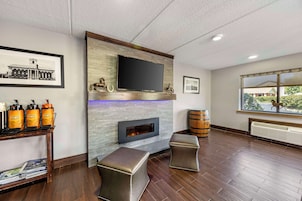 A modern living room with a fireplace, a mounted TV, and a window with a view.