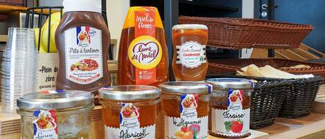 Variedad de alimentos, incluyendo frascos de conservas y salsas, sobre una encimera de madera.
