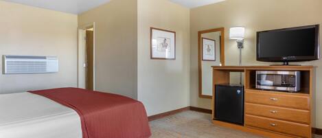 Quarto de hotel com cama, televisão, frigorífico e micro-ondas.