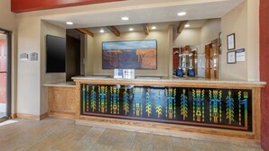 A reception area with a large flat-screen TV, a wooden counter with tribal art, and framed certificates on the wall. - Best Western Canyon De Chelly Inn (Chinle)