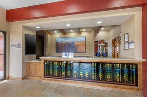 Un área de recepción con un televisor de pantalla plana grande, una barra de madera con arte tribal y certificados enmarcados en la pared.