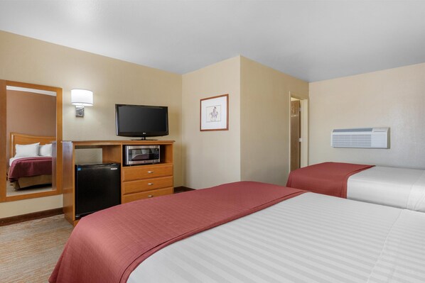 Habitación de hotel con cama, televisión, microondas, refrigerador, escritorio y puerta.