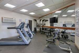Un gimnasio con cintas de correr, máquinas de pesas y pesas libres.