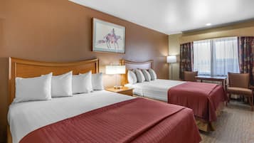 A hotel room with two beds, a desk, a chair, and a window with curtains.