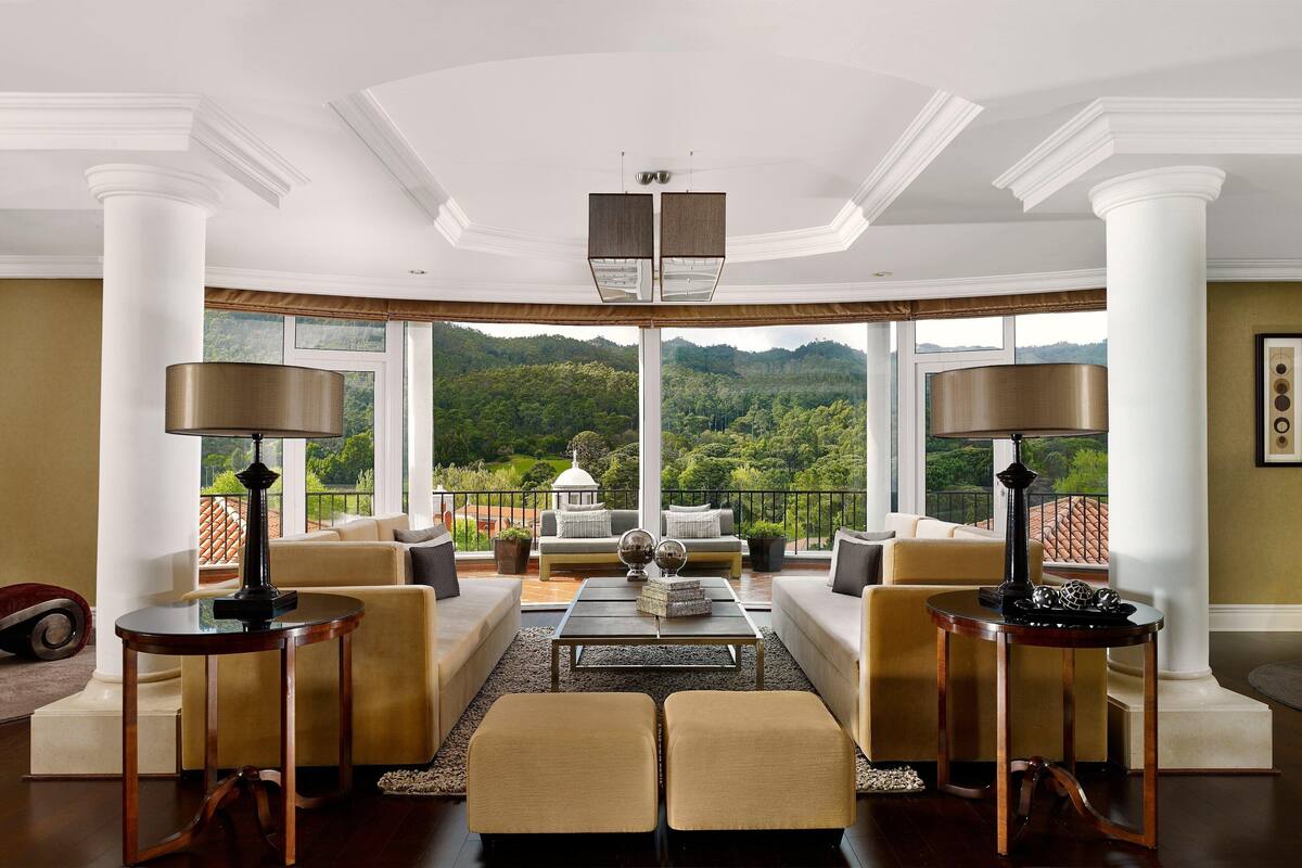A spacious living room with a large window offering a scenic view of a forested mountain.