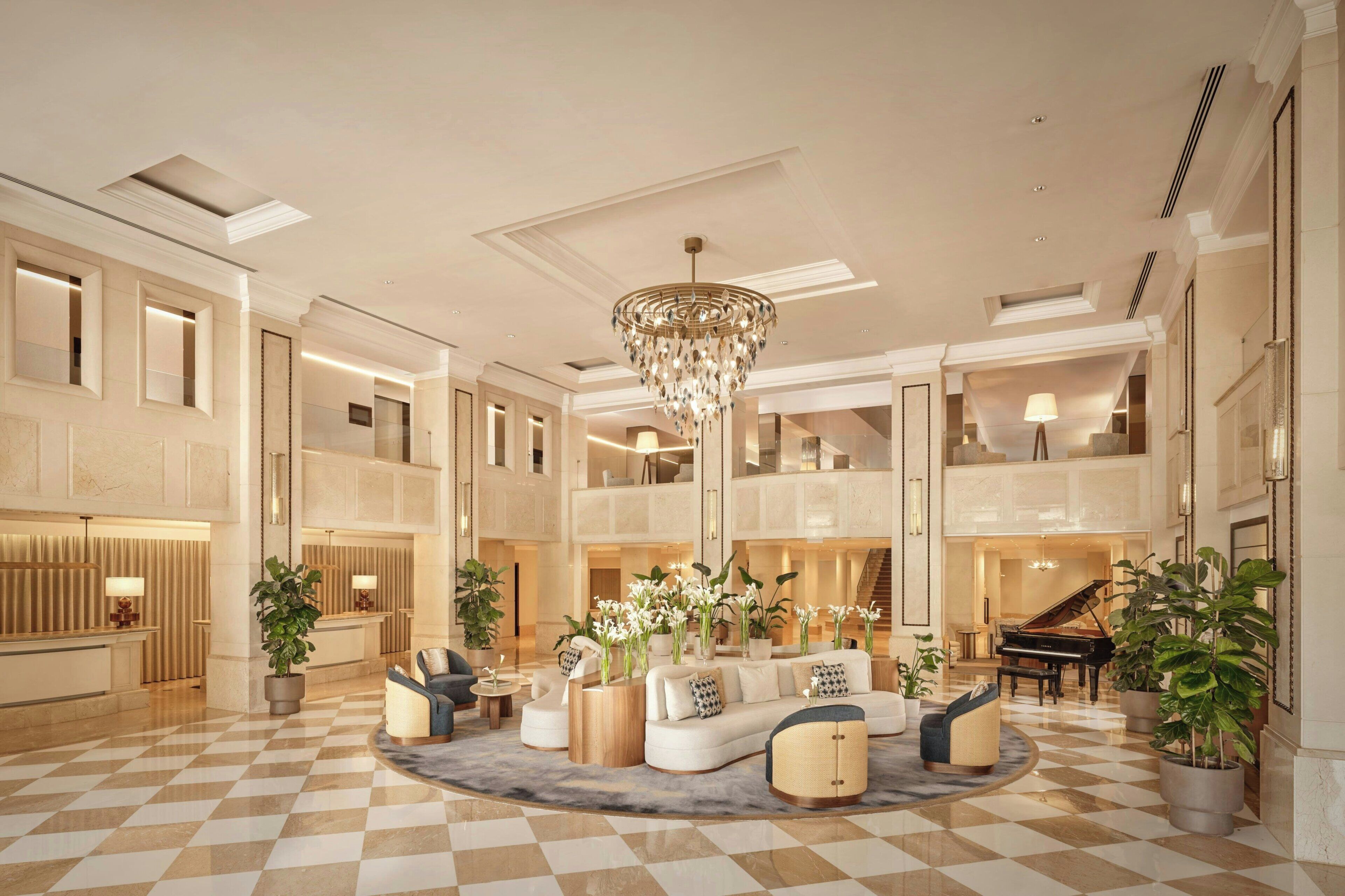Um hall amplo com piso xadrez, um lustre imponente e um piano.