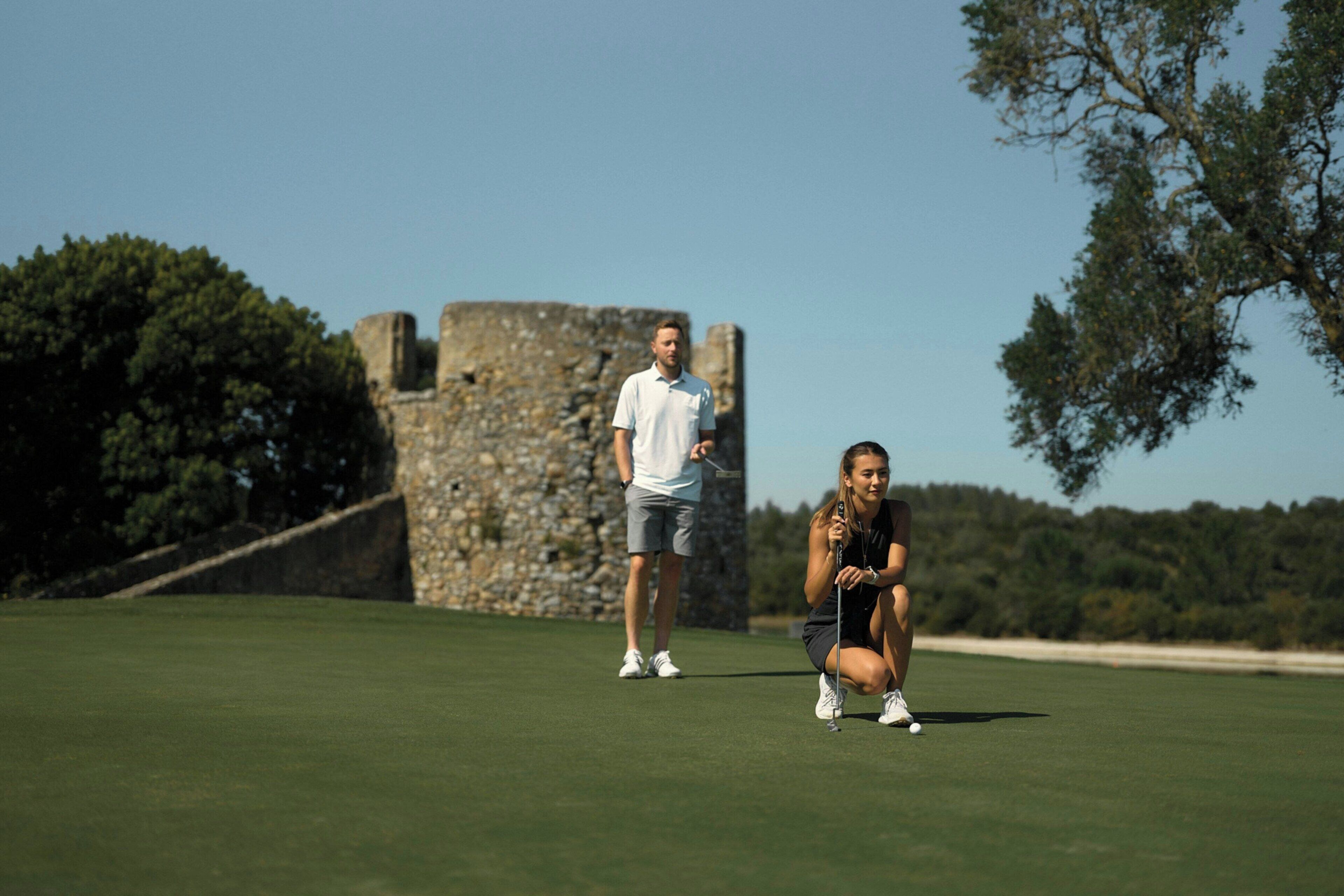 A golf course with a stone structure in the background.